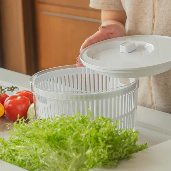 secador de saladas sobre a bancada com alfaces e tomates ao redor